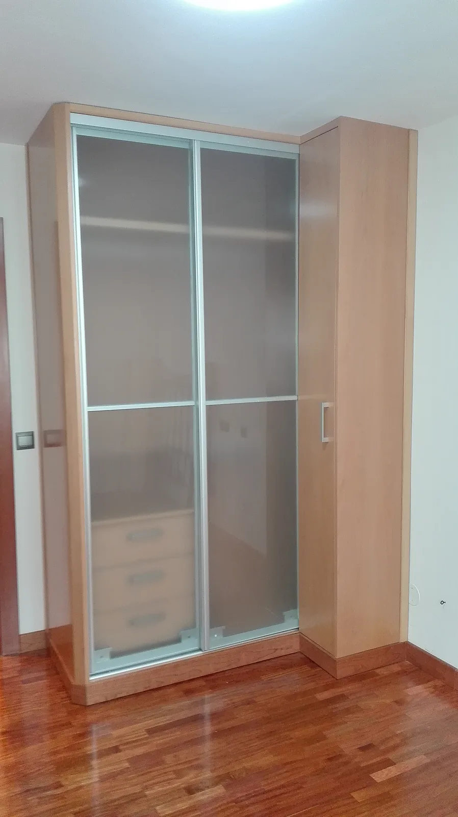 Armario con puertas correderas de cristal y perfiles de madera