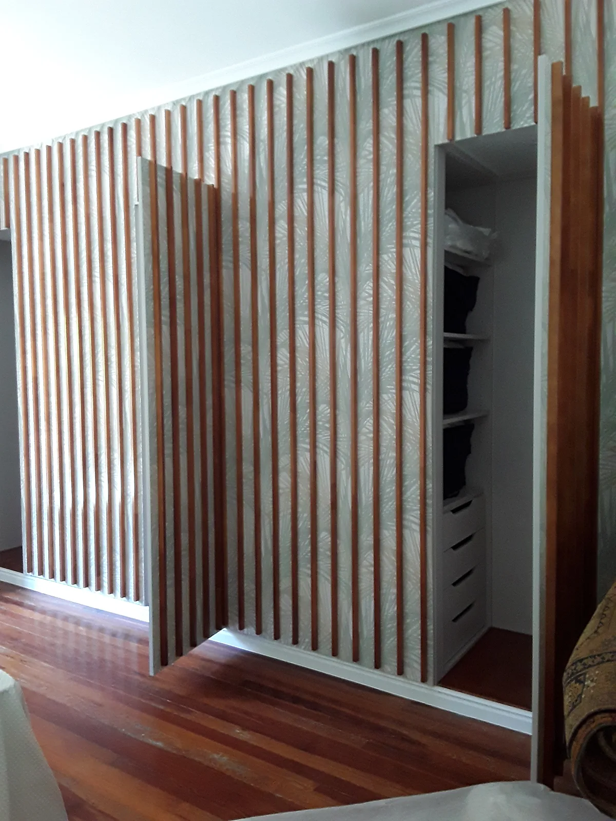 Armario empotrado oculto con listones de madera abierto mostrando el interior