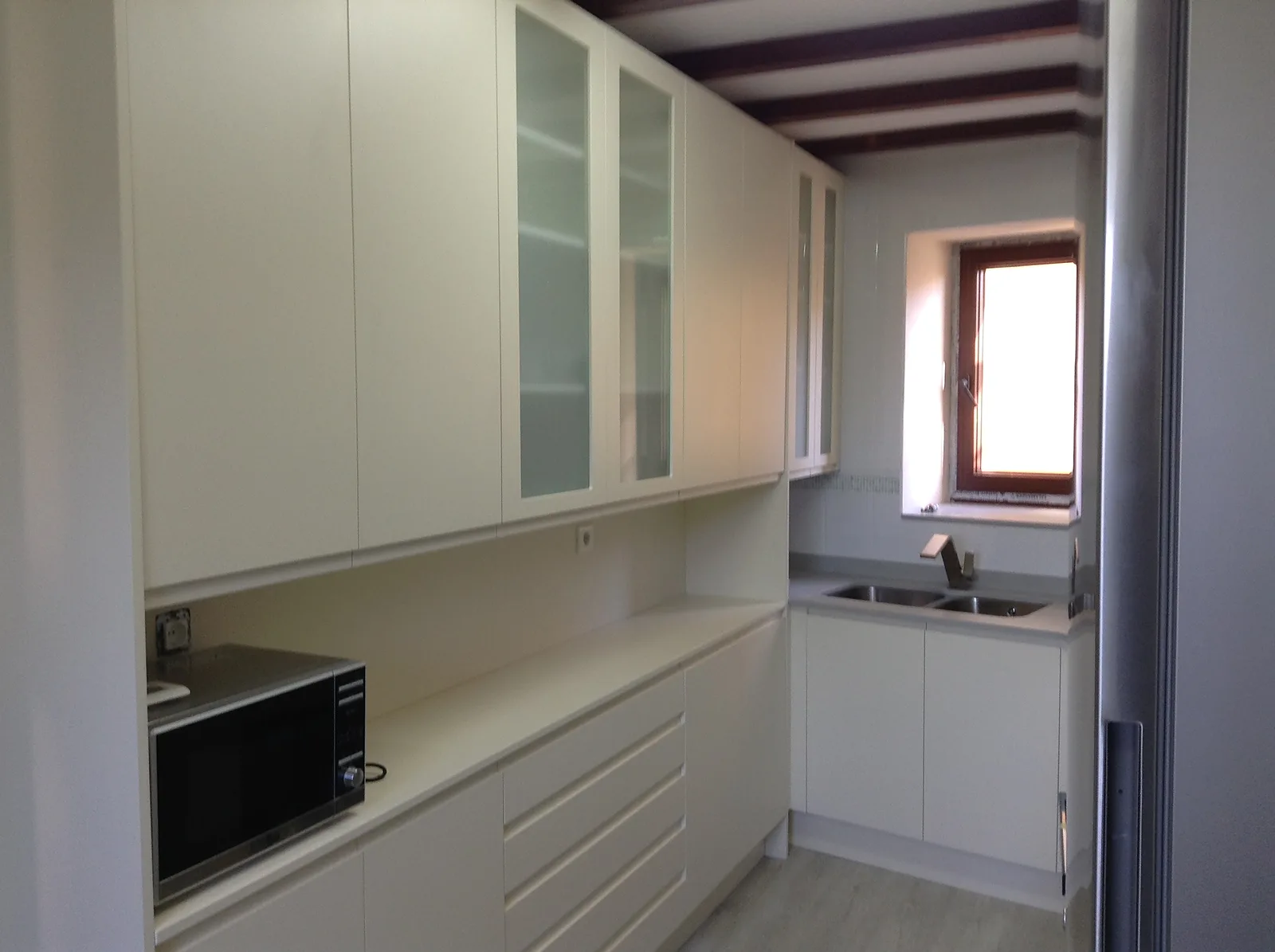 Cocina a medida en tono crema en casa con vigas de madera