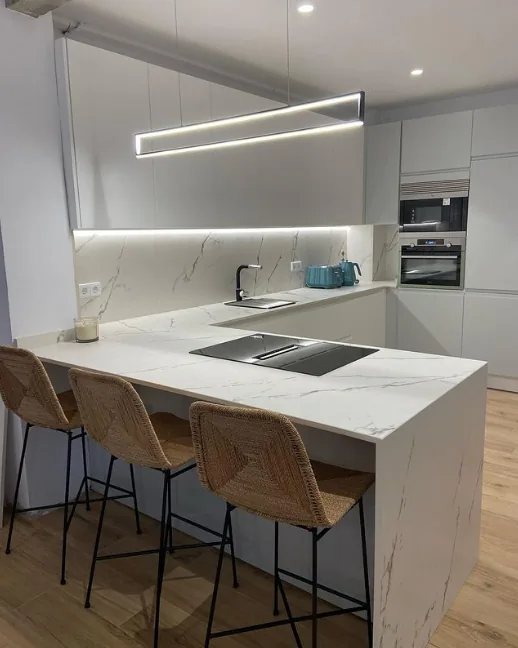Cocina a medida moderna blanca con isla y encimera de mármol en Santander