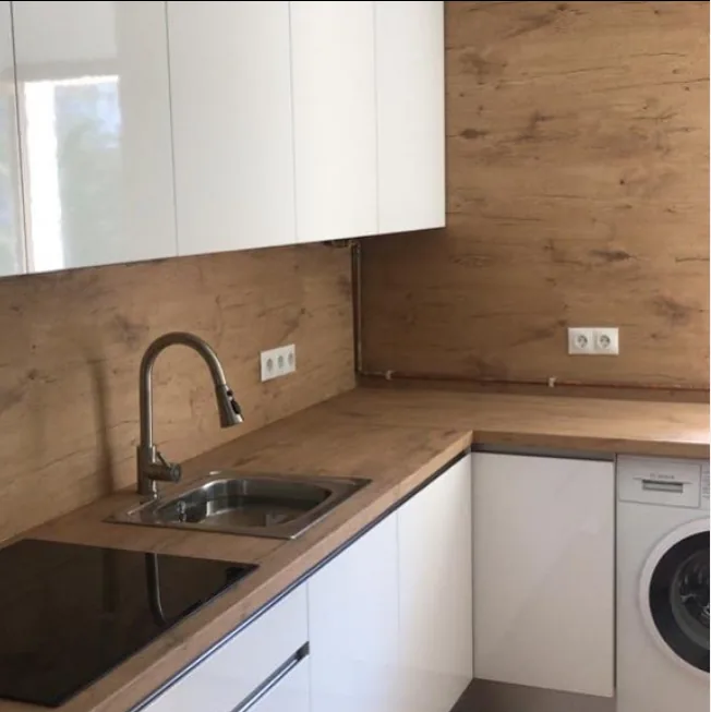 Cocina funcional a medida con revestimiento de madera y muebles blancos