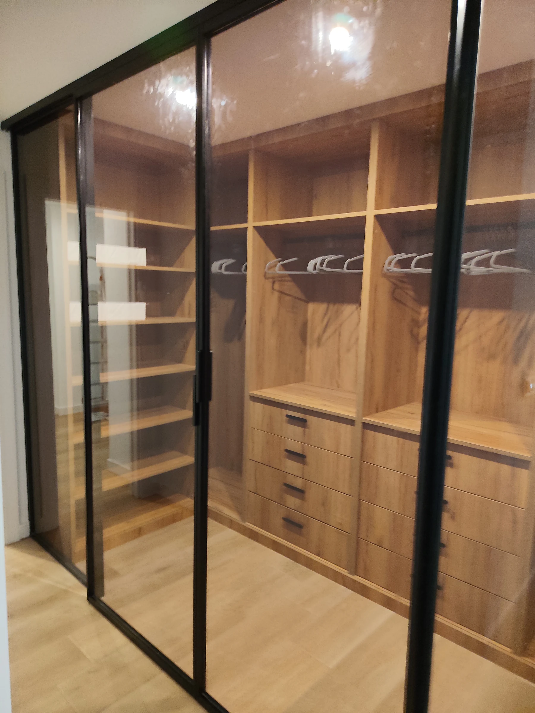 Vestidor a medida con puertas correderas de cristal y perfilería negra estilo industrial