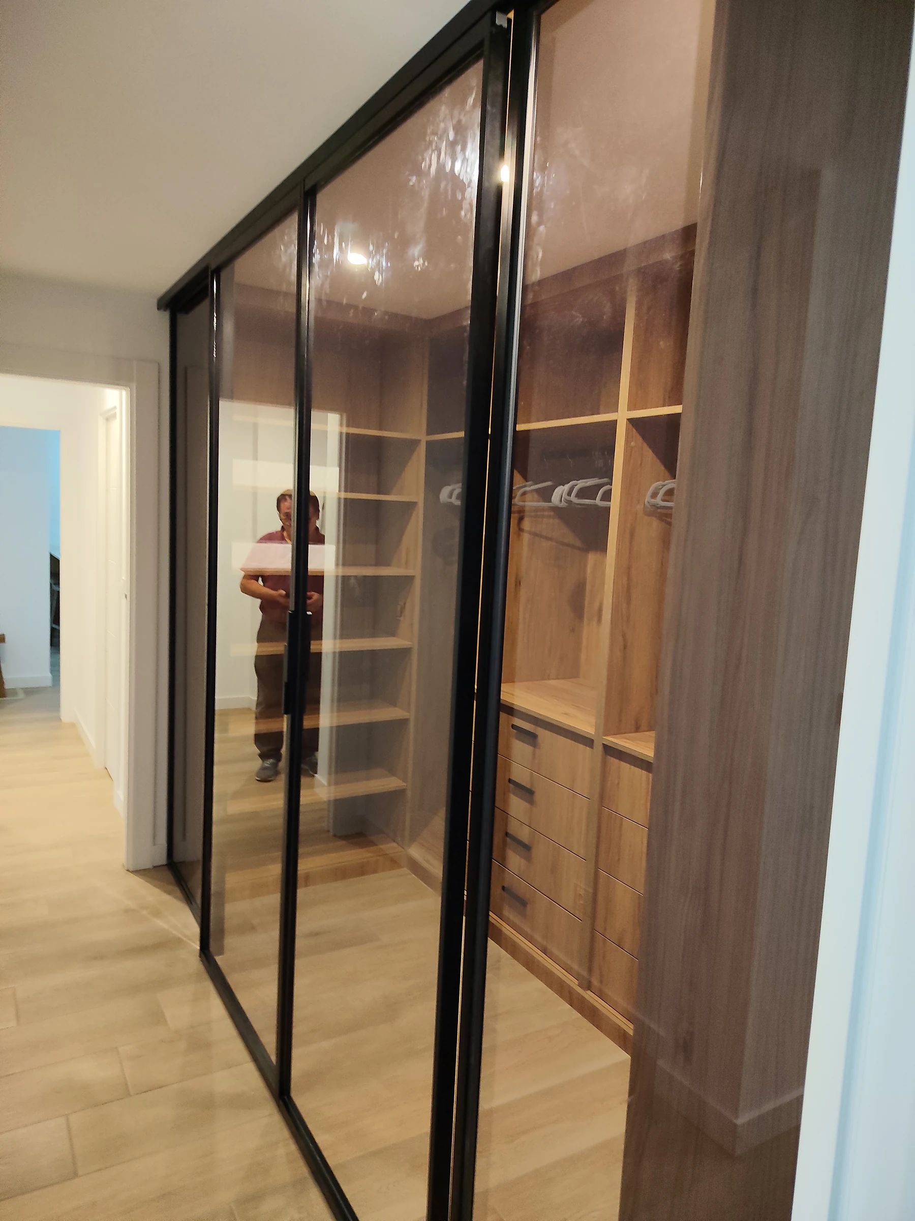 Vestidor con puertas correderas de cristal transparente, baldas y cajoneras en madera