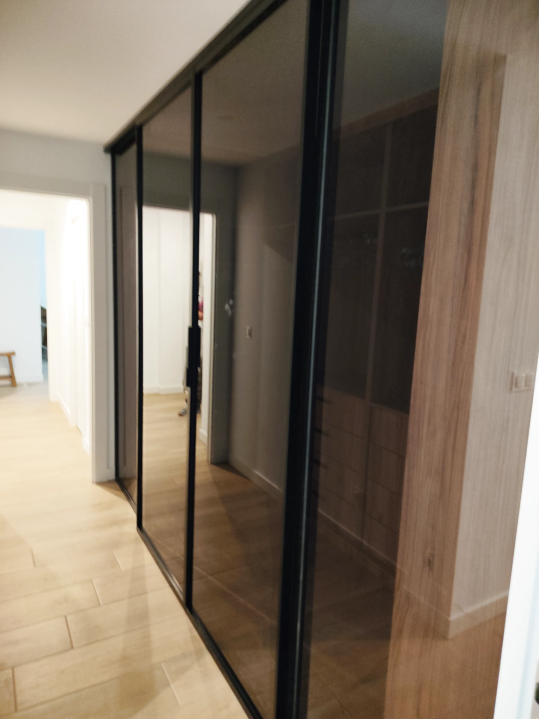 Puertas correderas de cristal ahumado con perfil negro en pasillo